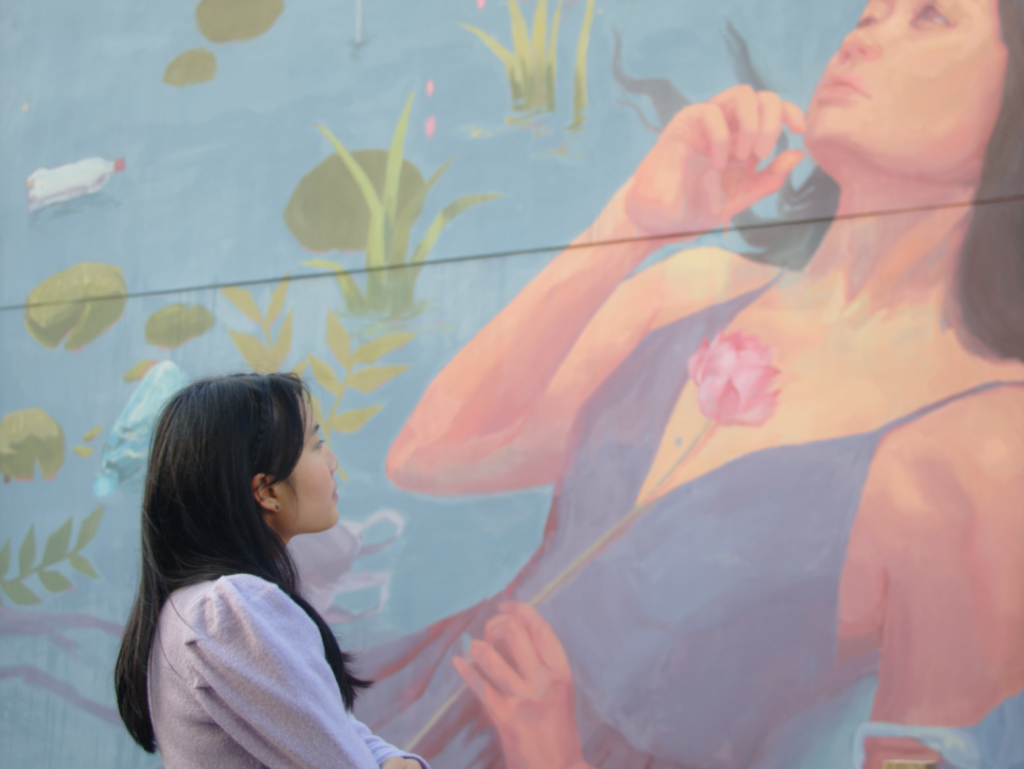 Monica Wat in front of street art ‘Longing’ by Caryn Koh, from the music video ‘Memories, Linger’.